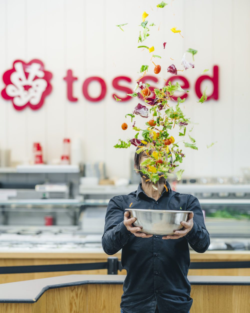 A salad being tossed into the air in front of a Tossed logo!